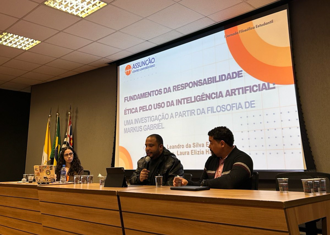 Alunos do Assunção apresentando seus trabalhos durante mesa de comunicação, com orientação da Prof.ª Dr.ª Natália Mendes Teixeira.